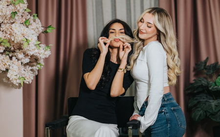 Two friends pose playfully in a cozy studio with hair mustache and smilesの写真素材