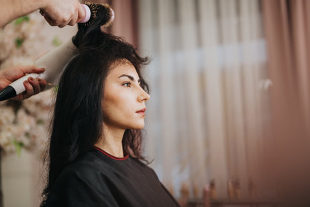 Woman receives professional hair styling in a salon during a calm, stylish makeoverの写真素材