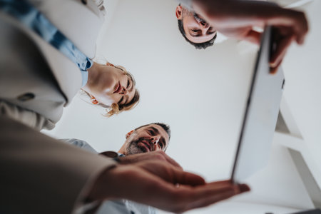 Diverse team huddles around tablet, discussing ideas and results during a collaborative office moment togetherの写真素材