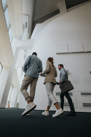 Business colleagues walk through a modern lobby, discussing plans in a bright, open space.の写真素材