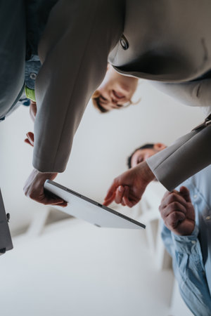 Colleagues Gather Over Tablet in Modern Team Meeting, Fostering Collaboration and Positive Workplace Spiritの写真素材