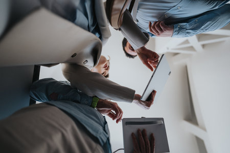 Colleagues review documents and tablet during a collaborative office meeting in a modern workspaceの写真素材