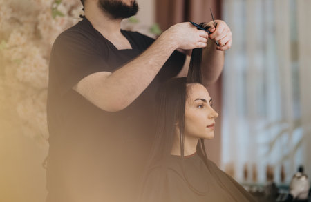 Woman getting a haircut at a stylish salon with a professional barberの写真素材