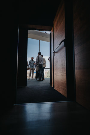 Colleagues stand in a doorway, talking outside during a break in a modern officeの写真素材