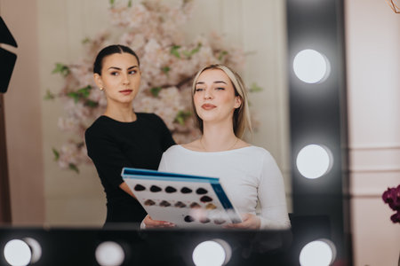 Two Women in a Beauty Studio Review a Fashion Catalog During a Professional Photo shootの写真素材