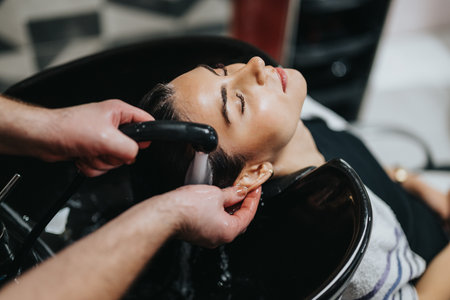 Woman receives hair wash at salon sink during professional hair care treatment, relaxing session todayの写真素材