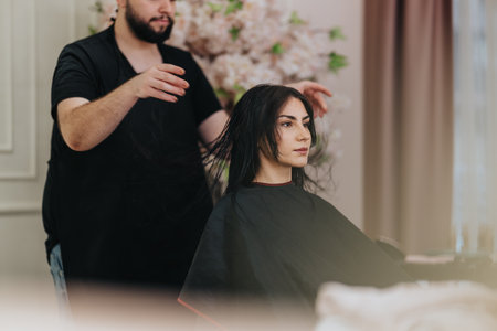 Woman receives a haircut at a stylish salon with a focused stylist and calm, modern atmosphereの写真素材