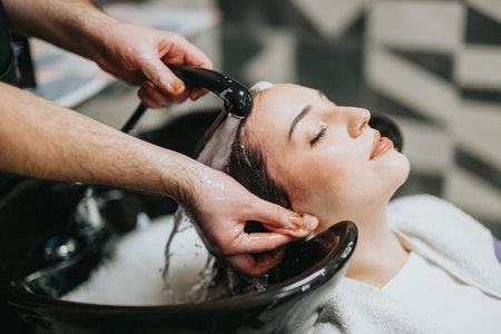 Relaxing salon spa treatment as stylist washes clients hair during a pampering sessionの写真素材