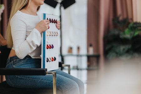 Woman sits in studio and studies color swatches with a fashion palette boardの写真素材