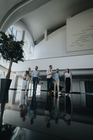 Group of professionals in a modern office lobby discussing ideas and planningの写真素材