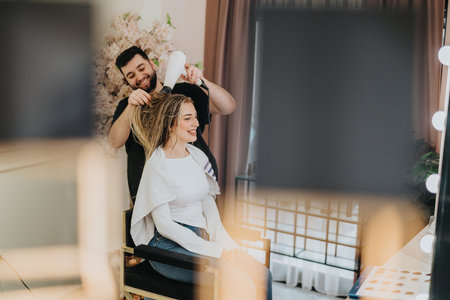 Happy woman receives a haircut at a stylish salon while a friendly stylist dries her hairの写真素材