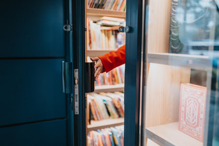 Woman opens bookstore door to colorful shelves and books in warm library sceneの写真素材