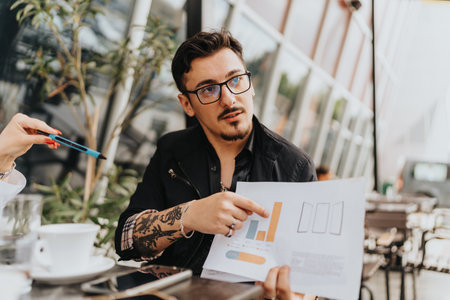 Businessman discussing analytics at outdoor cafe with team during a strategy meetingの写真素材