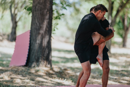 Outdoor wrestling training session between two men lifting a partner in a parkの写真素材