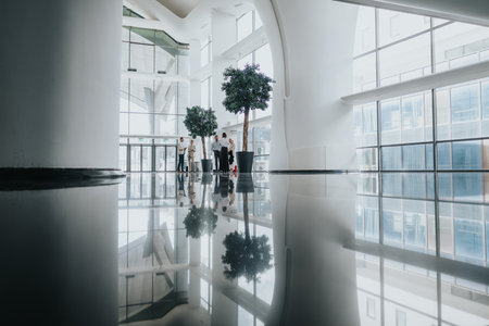Business colleagues gather in a bright modern lobby with glass walls and reflectionsの写真素材