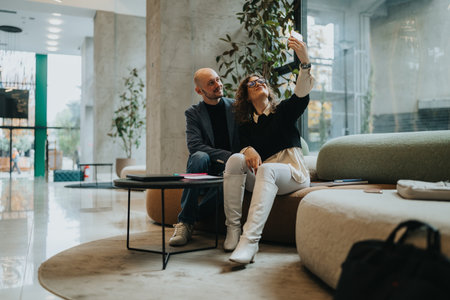 Business partners take a selfie in a modern lobby lounge during a casual meetingの写真素材