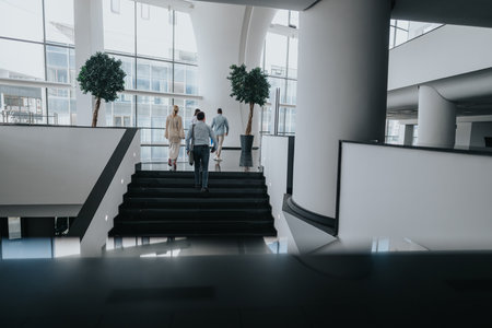 A group of colleagues walking up a modern staircase in a bright office atriumの写真素材