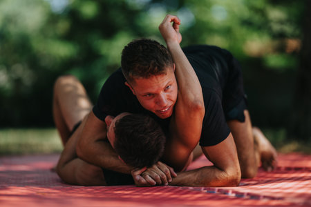Two athletes grapple on a red mat outdoors in a tense, athletic wrestling matchの写真素材