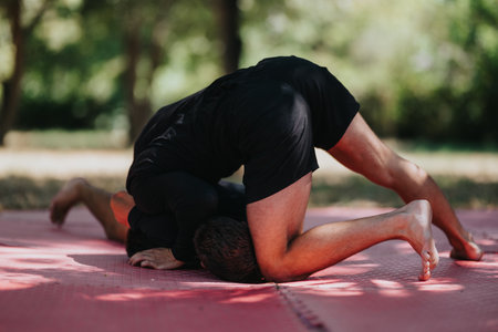 Intense wrestling drill on red mats in a park, two athletes training and grappling togetherの写真素材