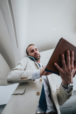 Business traveler in beige suit uses tablet and phoneの写真素材