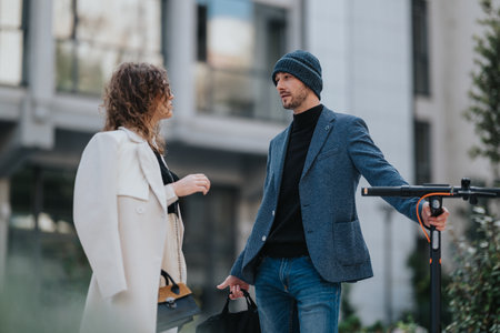 Stylish urban professionals chat on a city street with a blazer, beanie and electric scooterの写真素材