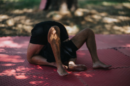 Person training on red mats outdoors, performing a wrestling drill in a shaded training areaの写真素材