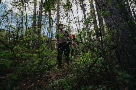 Hikers in a dense forest walk through trees and greenery during a daytime hikeの写真素材
