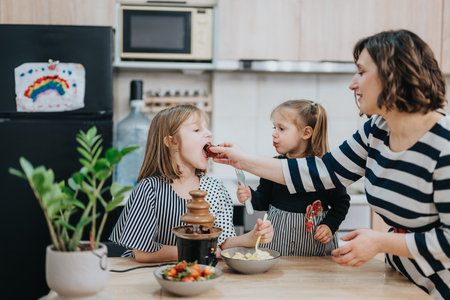 Family enjoying a chocolate fountain while spending quality time together at homeの写真素材