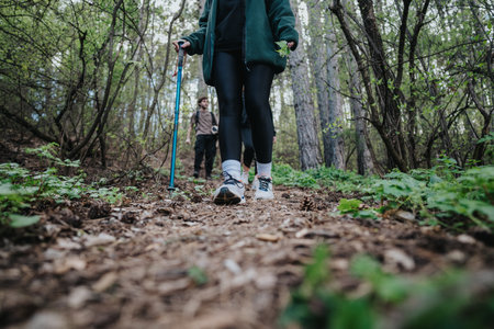 Hikers walking along a forest trail with trekking poles and sneakers in natureの写真素材