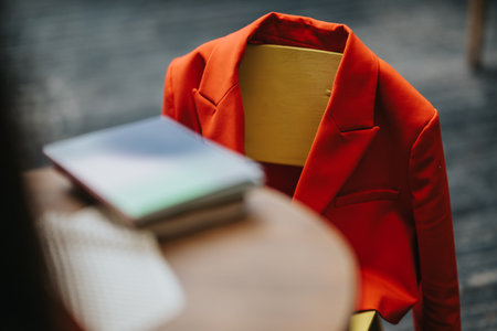 Red blazer on mannequin bust in a stylish workspace with books and tableの写真素材