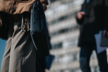 Two colleagues with bags and documents in an urban outdoor setting during a daytime momentの写真素材