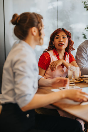 Casual business meeting among colleagues in a cafe, discussing ideas and teamwork during lunch breakの写真素材