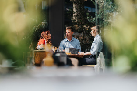 Business meeting outdoors at a cafe with colleagues discussing tablets and notes over coffeeの写真素材