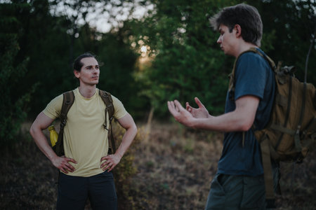 Two hikers talk in a forest clearing, sharing tips during a trekking tripの写真素材