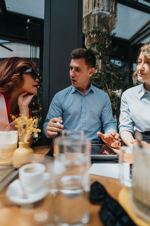 Business associates discuss ideas at a cafe table during a daytime meetingの写真素材
