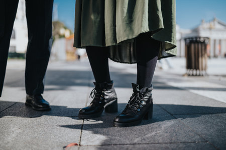 Stylish urban street scene with boots and coat, focusing on footwear and modern fashion on the sidewalkの写真素材