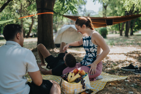 Outdoor picnic with friends and family at a park campsite, sharing fruit and laughter togetherの写真素材