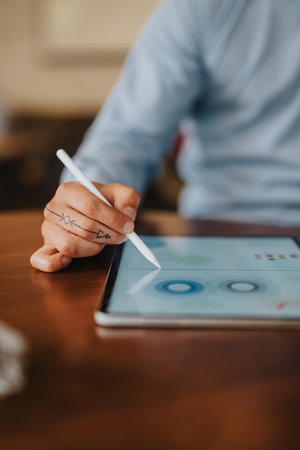 Person using stylus on tablet to design a digital interface and sketch ideas at a deskの写真素材