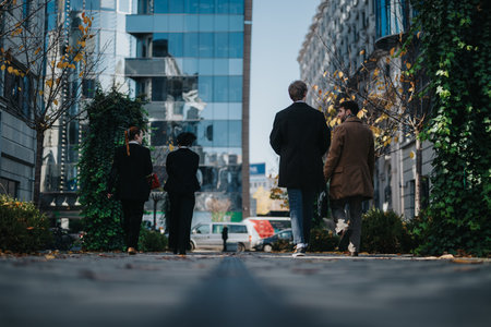 Business colleagues walking on a city street in autumn among glass buildings and ivy-covered wallsの写真素材