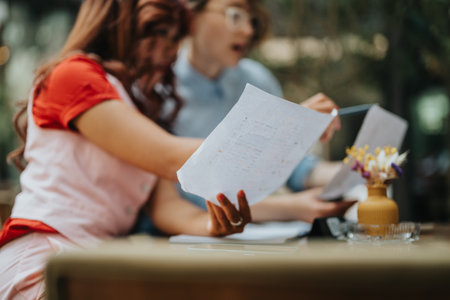 Friends review documents at a desk in a casual business setting with papers and flowers