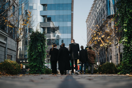 Group of colleagues walking together down a city street with modern glass buildingsの写真素材
