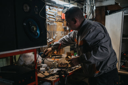 Mechanic at work in a cluttered workshop repairing electronic equipment and speakersの写真素材