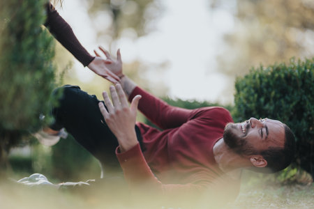 Happy man in red sweater lying on grass in park reaching for a high fiveの写真素材