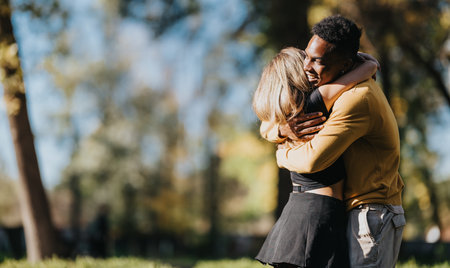 Two friends share a warm hug in a sunny park, celebrating connection and joyful togethernessの写真素材