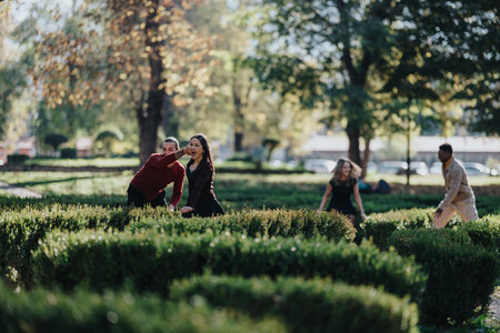 Friends playfully explore a hedge maze in the park on a sunny dayの写真素材