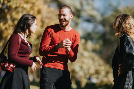 Three friends enjoying a sunny park conversation and laughter outdoorsの写真素材