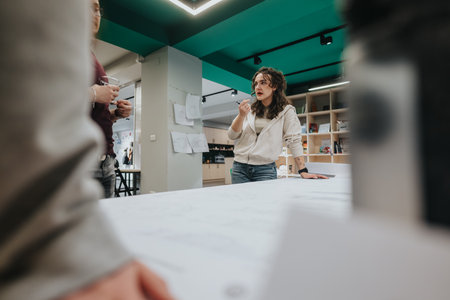 Woman presenting ideas during a team discussion in a modern collaboration center with colleaguesの写真素材