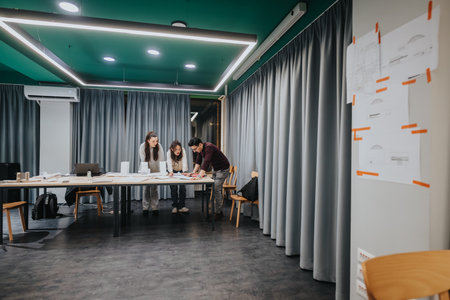 Group of students collaborates at a modern study center with papers and laptops