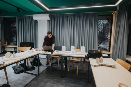 Student at collaboration center, working on laptop and architecture models in a modern study spaceの写真素材