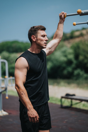 Athletic man training outdoors on a sunny day with gym equipment